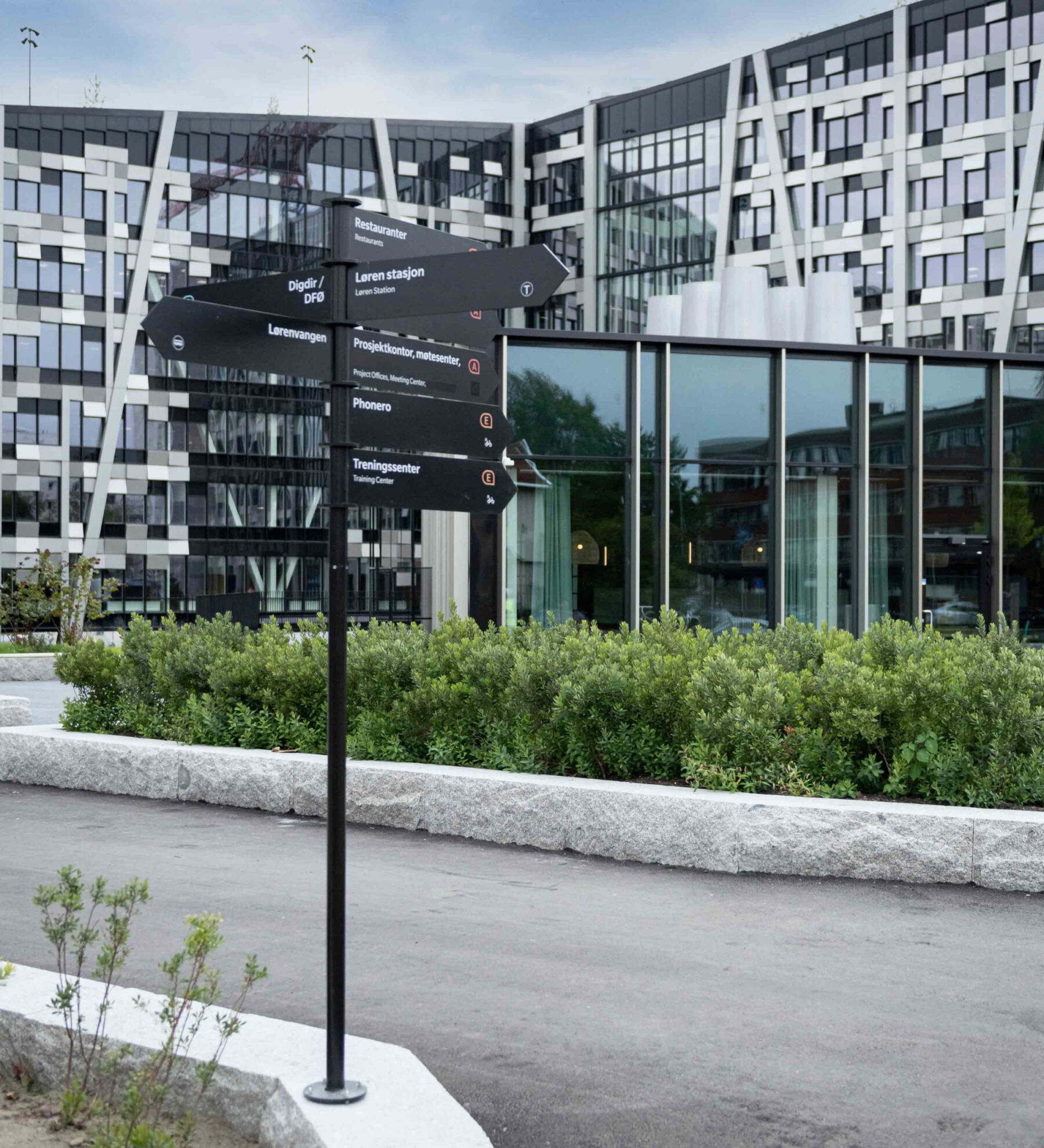 Utendørs skilting på Økern Portal. Skimter stor bygning med masse vinduer i bakgrunn. Foto