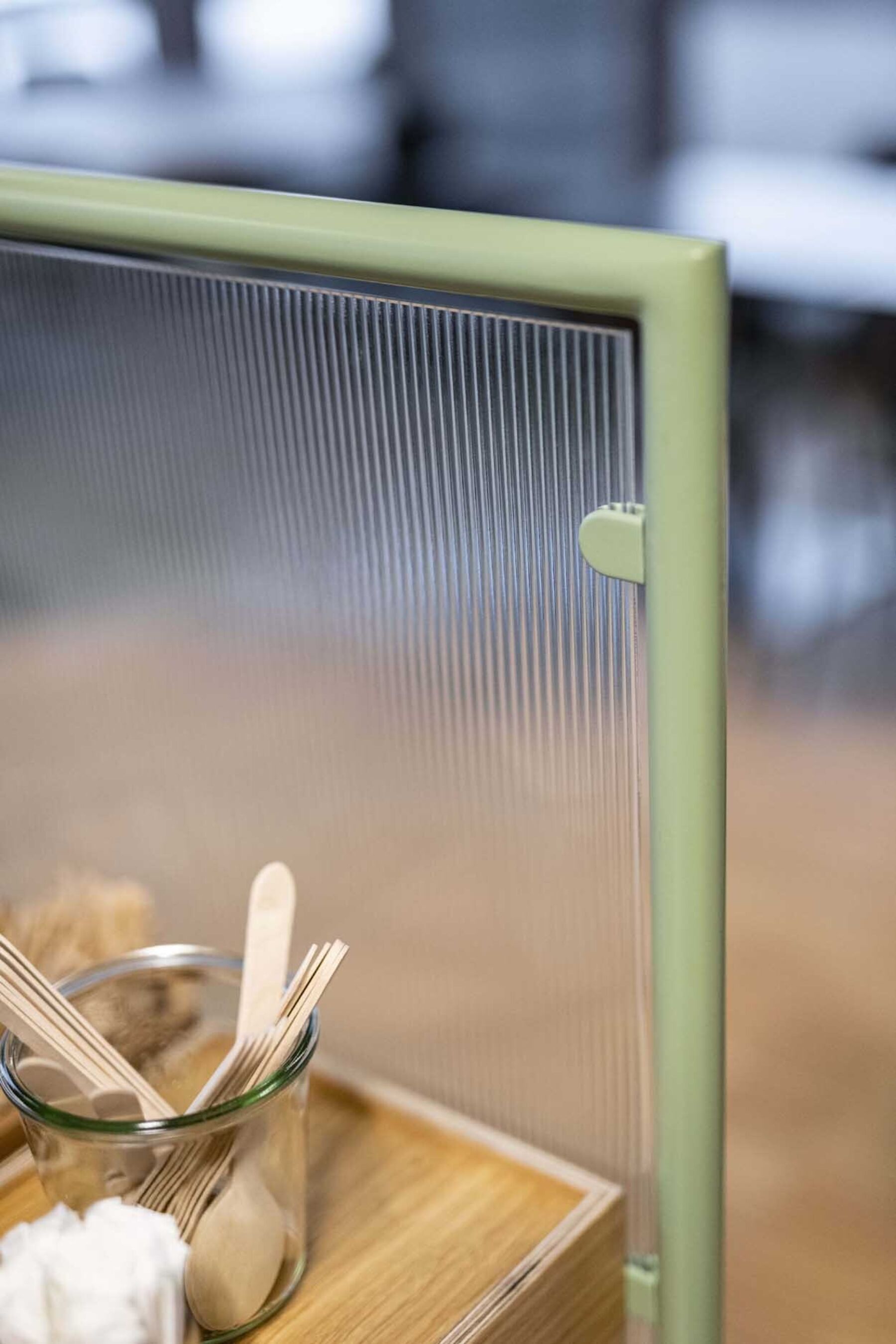 Detaljer av kaffestasjon i kantine. Rillet glass med grønn matallramme. Foto.